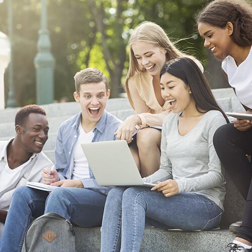 Group of excited students looking at a laptop