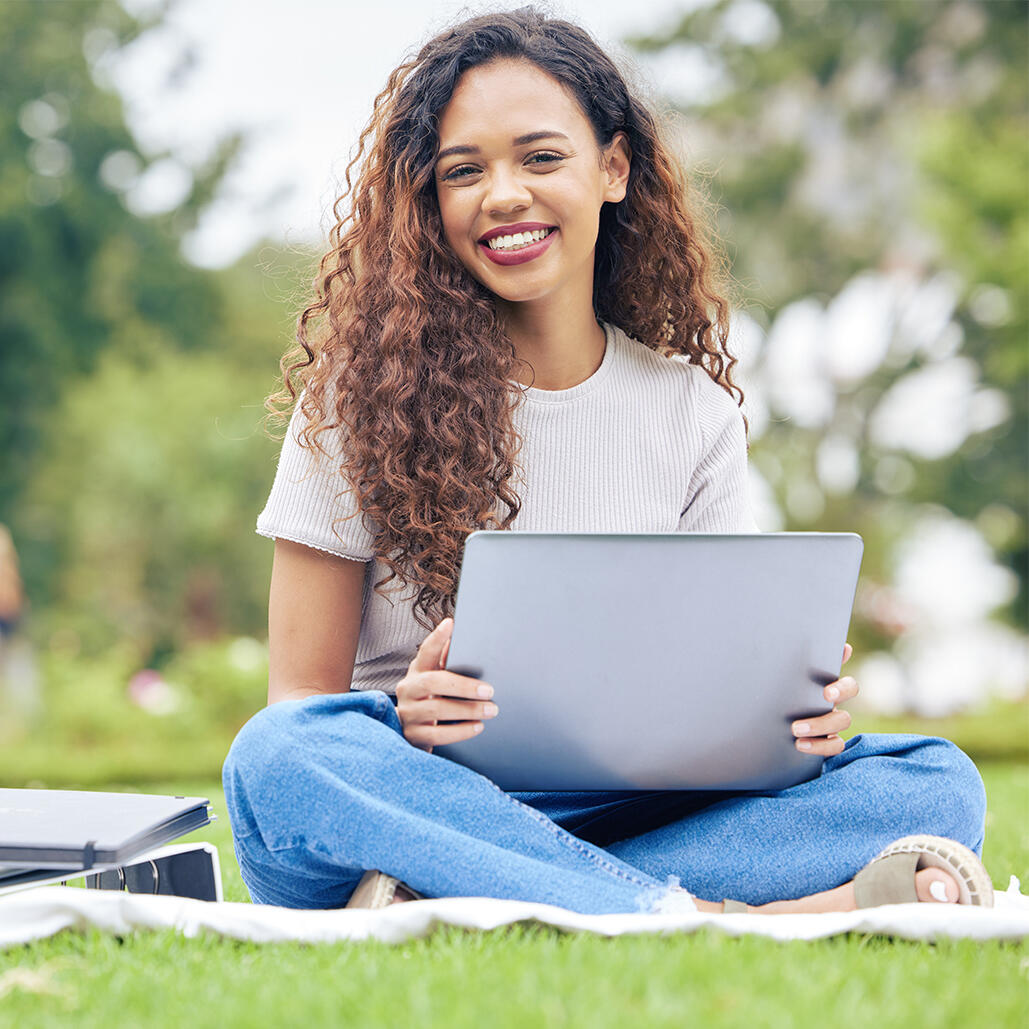 Young female law student smiling while using her computer to study online on her university campus.