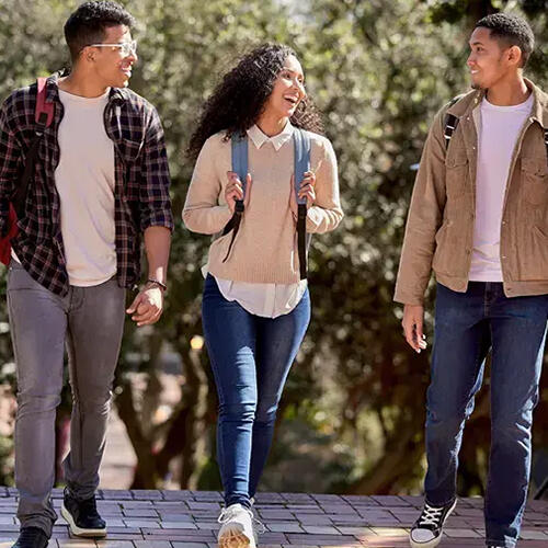 Three students engaged in conversation and laughing as the walk together.