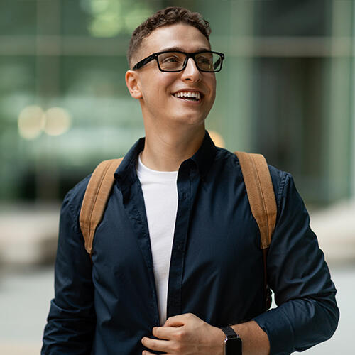 Male student wearing glasses and a backpack looking up