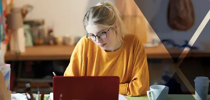 A student studying at a desk with laptop  