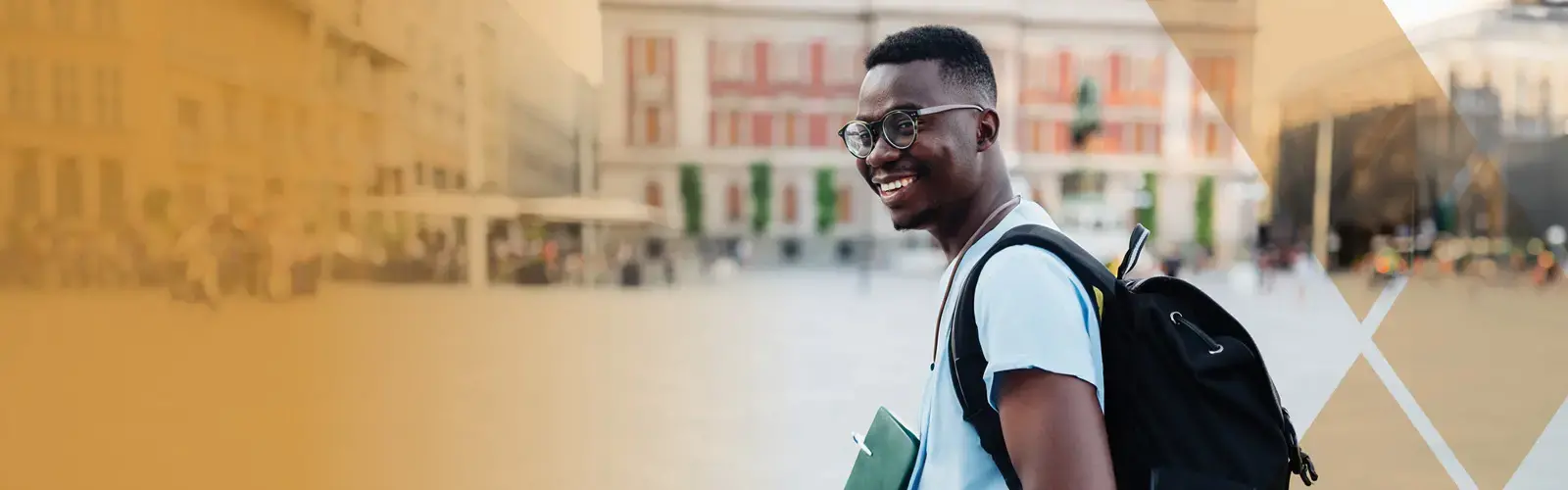 Young adult with eyeglasses walking on street with a backpack and notebooks in his hand 