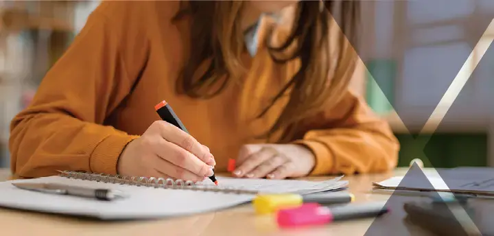 Woman highlighting text on document with highlighters on a desk 