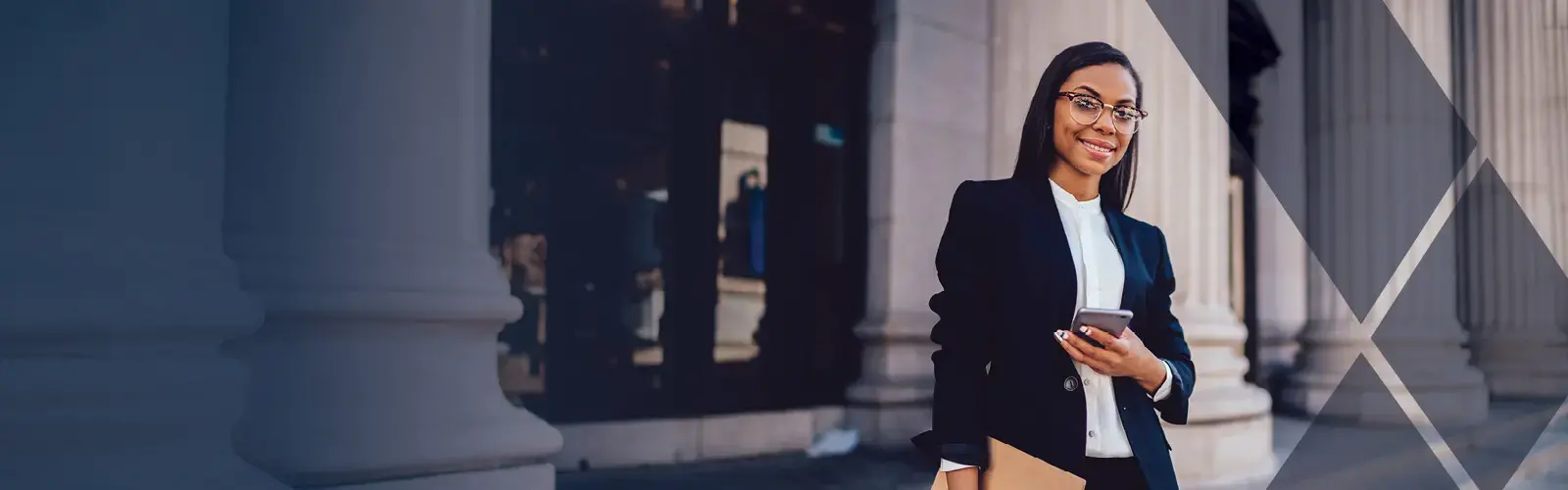 A young lawyer on the steps of a courthouse holding a mobile phone and folders. 