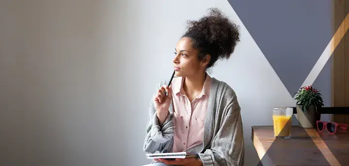 Young adult sitting at home with pen and paper 