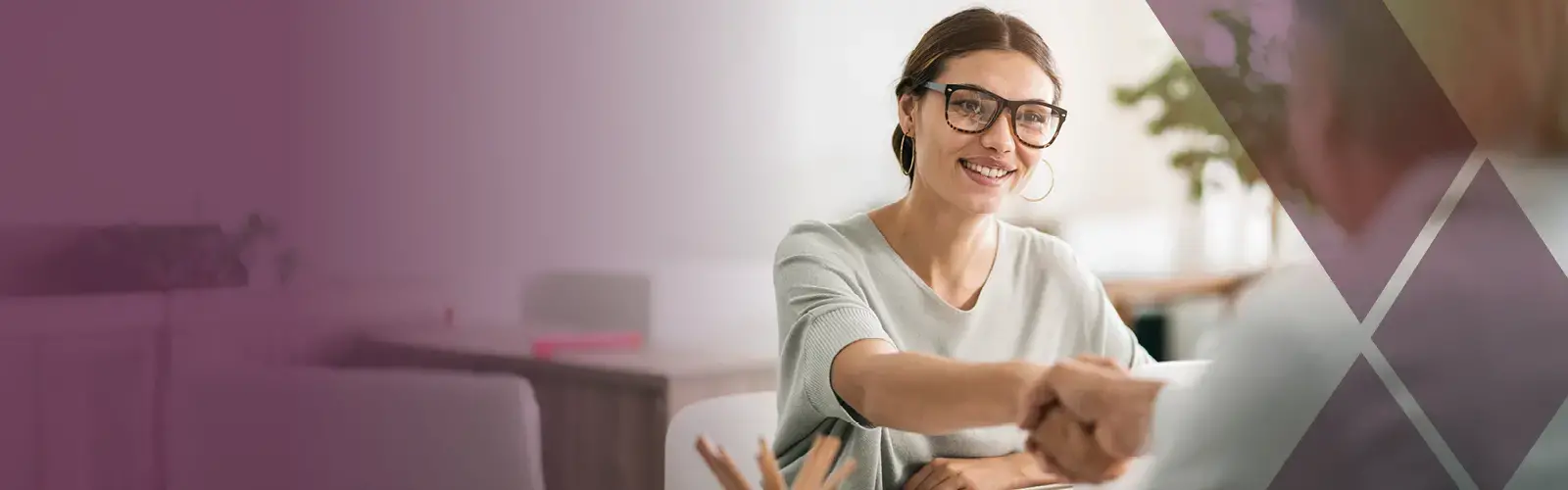 Young professional shaking hands across a desk 