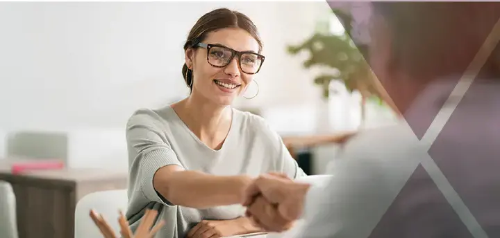 Young professional shaking hands across a desk 