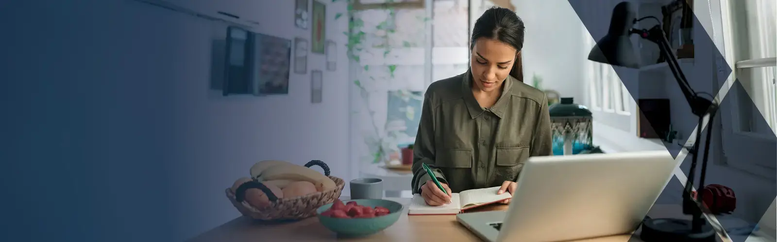 Young adult sitting at desk taking notes in notebook 