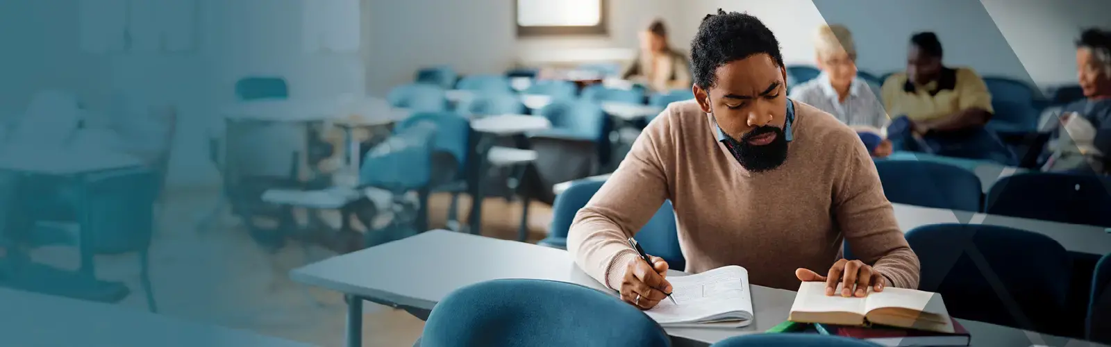Mid adult student taking notes while learning in the classroom 