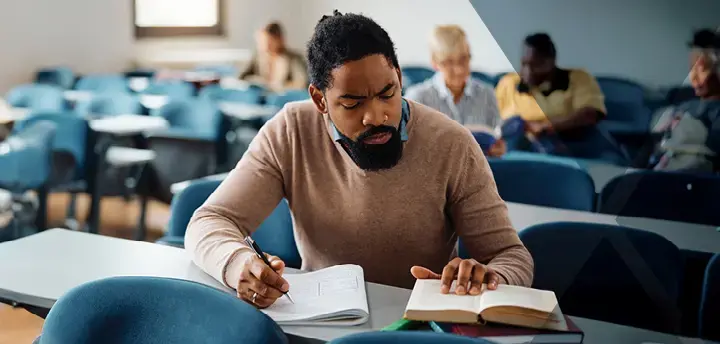 Mid adult student taking notes while learning in the classroom 