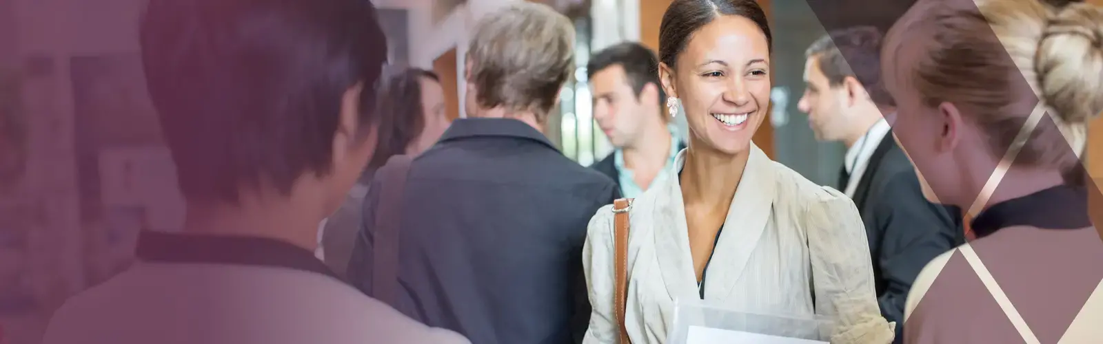 Portrait of two smiling adults holding files and talking, standing in crowded lobby 