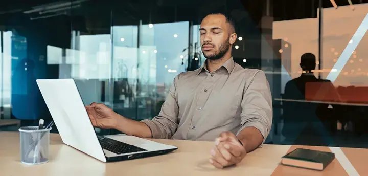 Business person working inside modern office building meditating with eyes closed sitting on chair 
