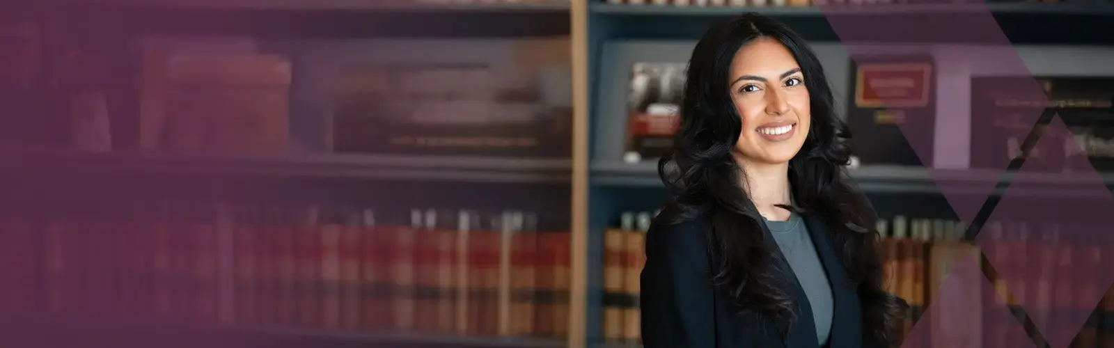 Confident lawyer standing in front of a bookcase of legal books and smiling at the camera