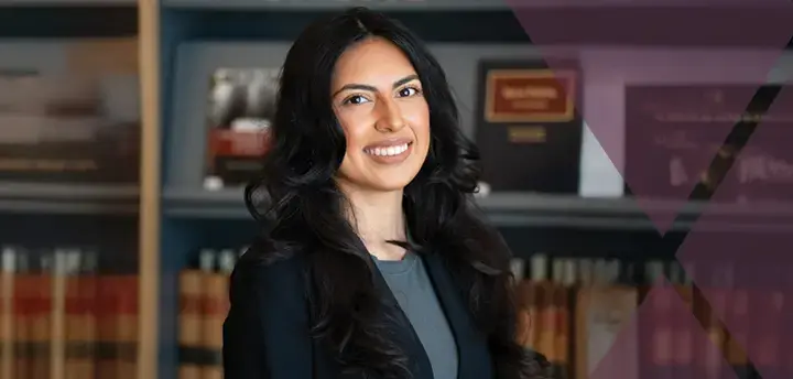 Confident lawyer standing in front of a bookcase of legal books and smiling at the camera
