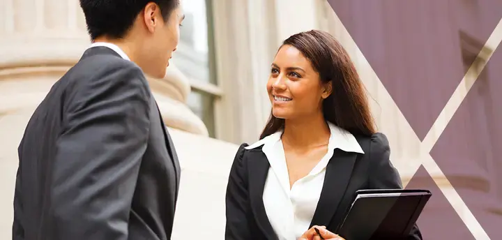 Professional woman and man having a discussion on the stairs of a stately building. The woman is holding a notebook.