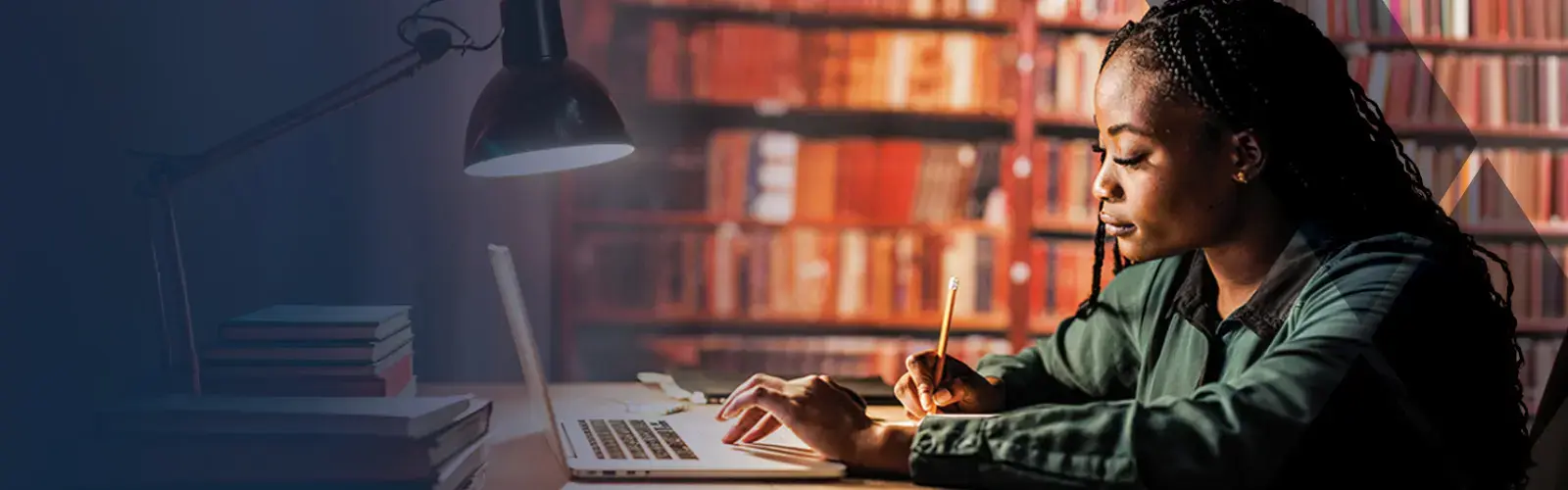 Diligent young female student sitting at table at the library, using laptop and writing notes while studying for Washington Bar Exam.